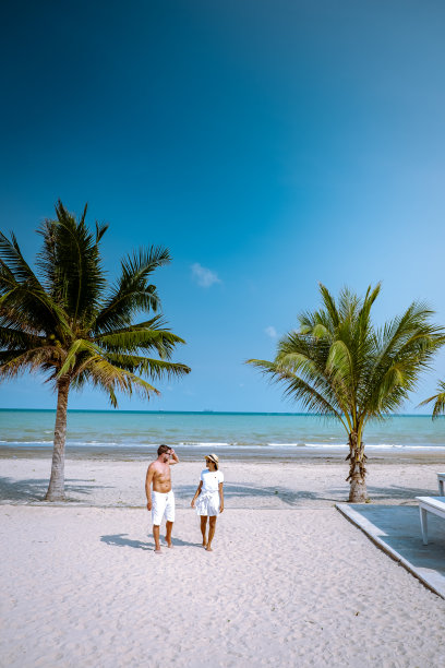 一对夫妇在泰国春丰地区的海滩上棕榈树和蓝色的海洋在阿鲁泰海滩日落图片下载