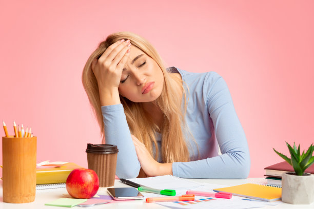 疲惫的少女坐在桌旁摸着头图片下载