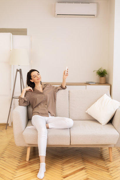 年轻女子打开家里的空调图片下载