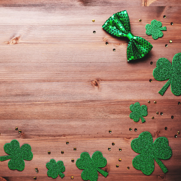 圣帕特里克节贺卡，带有传统符号，三叶草，绿色服装。绿色的帽子，领结，圣帕特里克节三叶草，金色的纸屑木制背景，复制空间图片下载