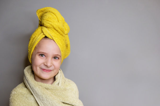洗完澡后，美丽微笑的小女孩在毛巾里的工作室肖像。图片下载