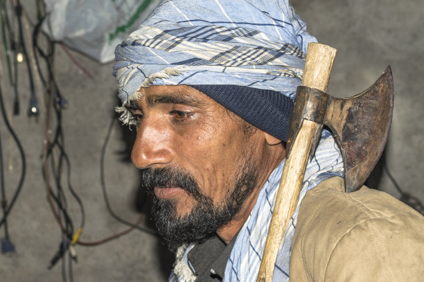 一名亚洲农民面带微笑，肩上扛着传统的斧头图片下载