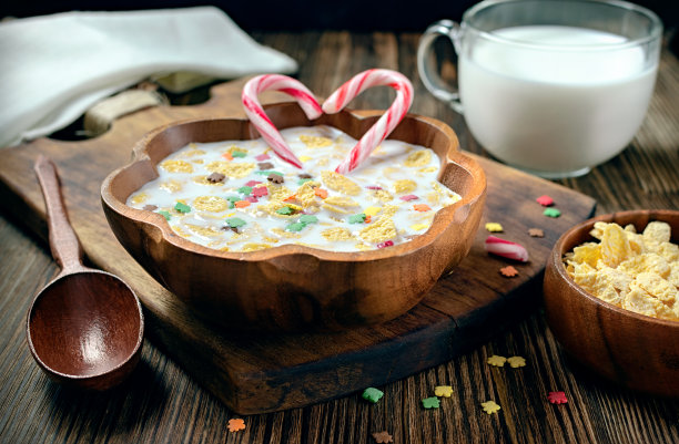 环保木盘里的牛奶玉米片和焦糖棒，情人节早餐，木质背景上的甜点图片下载