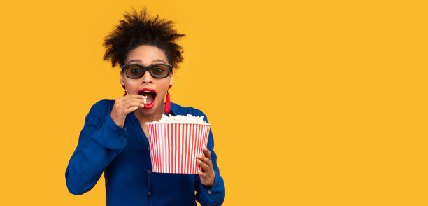 千禧一代非洲裔女子拿着爆米花看向镜头图片下载