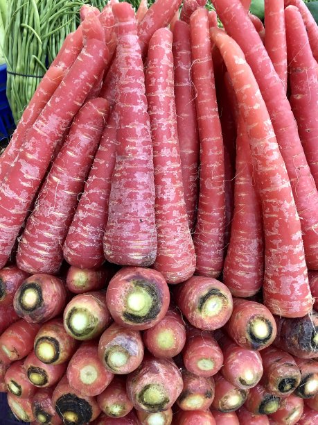 印度当地的新鲜农产品市场的图像，近距离观看红色的胡萝卜和大葱叶图片下载