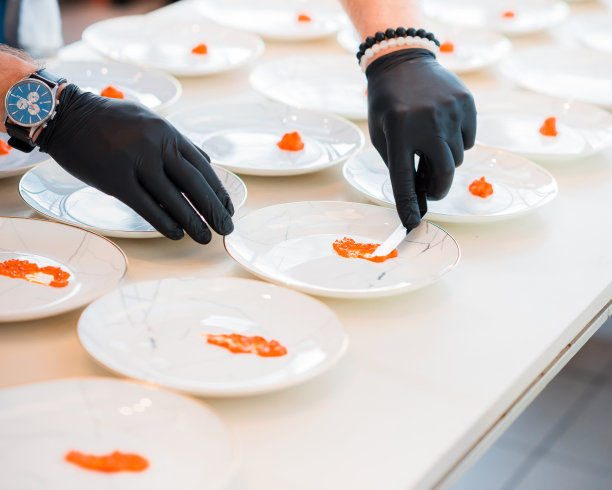 厨师在厨房台面上将食物摆放在白色盘子里图片下载