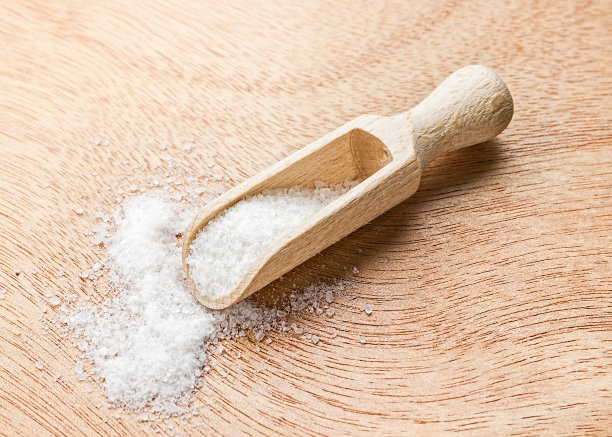 用木勺舀海盐。木质背景上的白色海盐。木勺里的海盐。图片下载