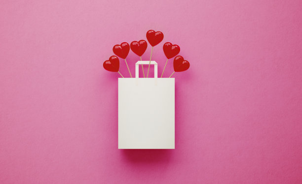 粉色背景下白色购物袋里盛开的心形棒棒糖图片下载