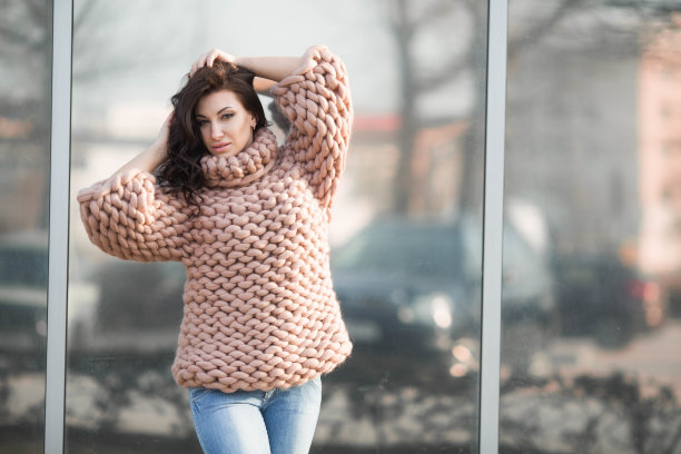 一个女孩穿着暖和的针织毛衣在街上图片下载