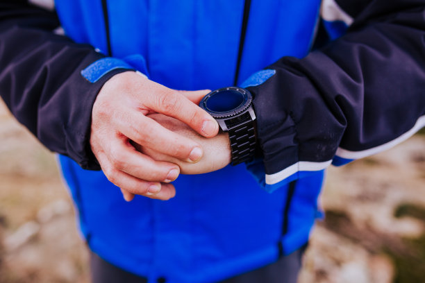 一名年轻的徒步旅行者在山顶上看智能手表。多云的一天图片下载