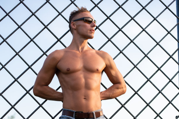 一位健壮的男人在铁栅栏后摆姿势图片下载