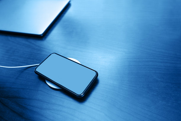 移动智能手机无线充电通过共享电池的设备在经典的蓝色。图片下载