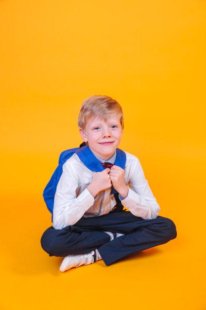 一个背着书包的小男孩坐在橙色背景上图片下载