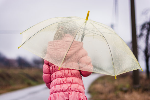 孩子撑着伞在下雨。图片下载