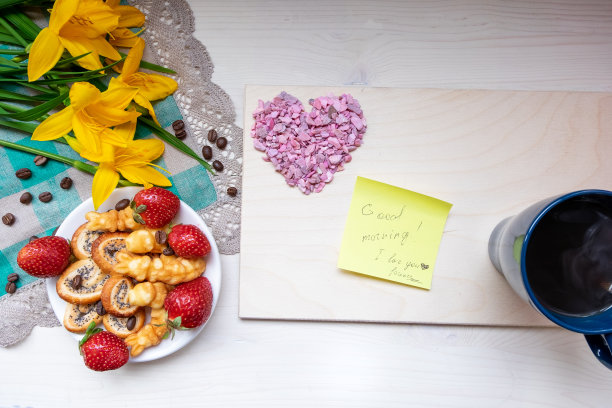 情人节草莓饼干、咖啡、黄色鲜花、餐巾、记事本和笔，以及写着“早上好，我爱你”的纸条图片下载
