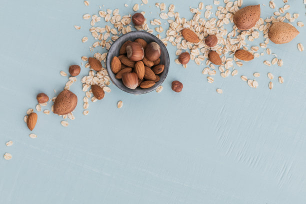 干燕麦片，小麦穗，榛子和杏仁坚果在浅绿色的背景。小麦种子的背景图片下载