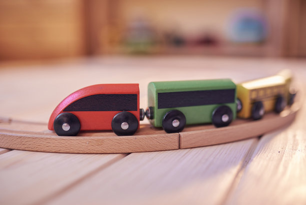 木制玩具火车在轨道上与散焦儿童的房间在背景图片下载