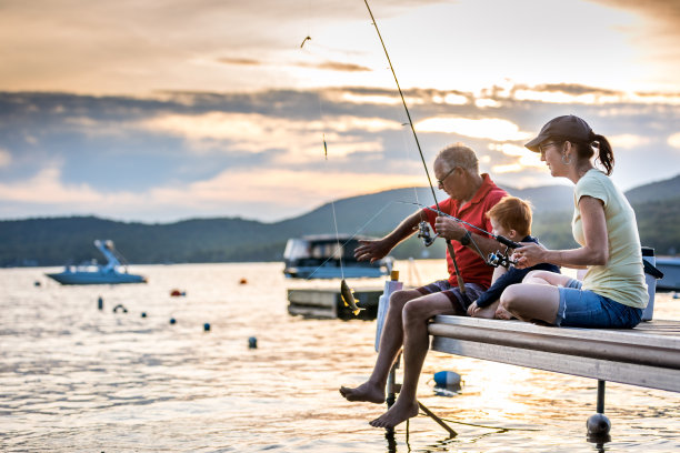 爷爷、妈妈和孙子在夏天的日落钓鱼图片下载
