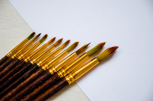 一组不同大小的画笔，用于在米色背景上使用颜料作画。图片下载