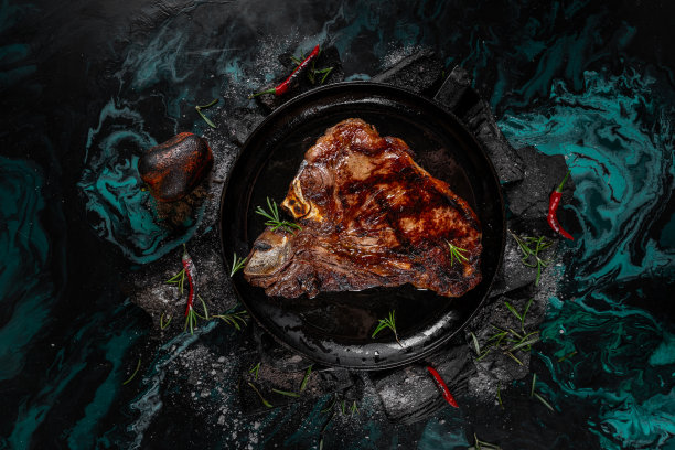 炸牛排上的黑色木炭背景。在炭火上熏熟多汁的牛排，配上迷迭香。烤美味的腌牛排在煤炭上，特写照片。图片下载