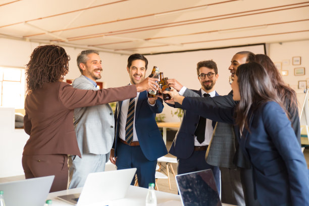 微笑的办公室经理们用啤酒瓶欢呼图片下载