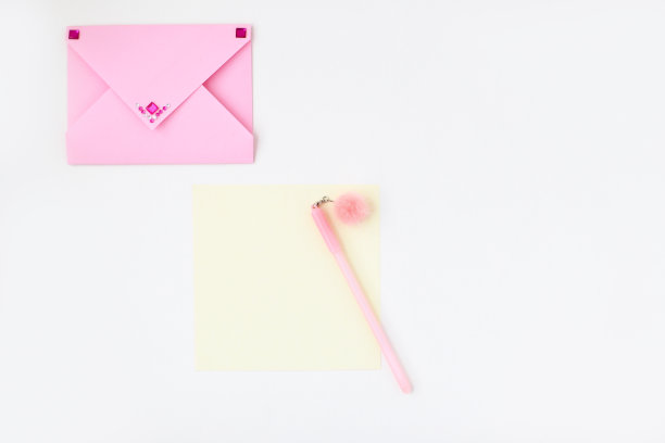 平铺:黄纸，镶着水钻的粉色信封，带绒球的钢笔。在信封里制作情人节明信片。做你自己。系列图片图片下载