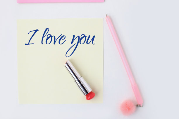 平躺:黄色的纸，粉色的笔，绒球，口红，文字-我爱你。在信封里制作情人节明信片。做你自己。系列图片图片下载