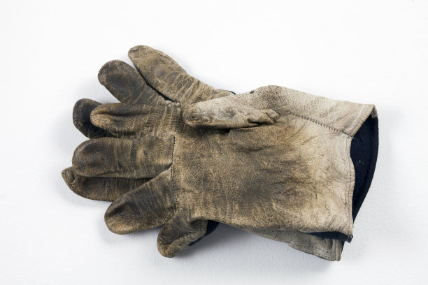 白色的背景上放着一只又旧又脏的工作手套图片下载