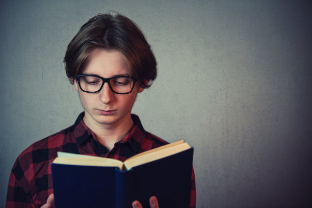 戴眼镜的男学生专注读书特写：为考试和学习做准备。图片下载