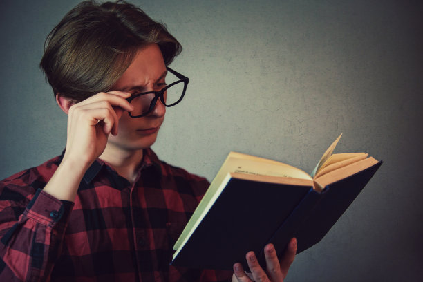 视力不佳的年轻男学生正在看书图片下载