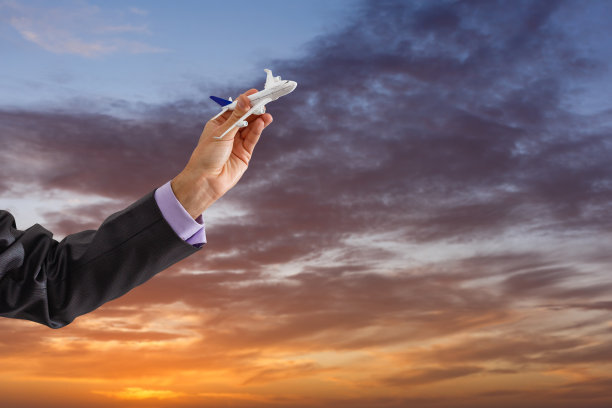 男人手持玩具飞机，以蓝天白云为背景特写图片下载