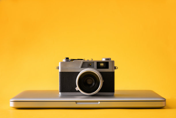 黄色背景上的笔记本电脑和相机图片下载