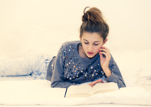 女孩躺在床上看书图片下载