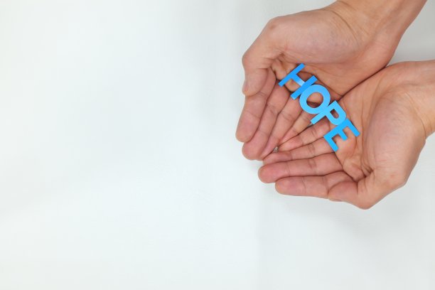 双手捧着白色背景中的“希望”字样剪纸。传递希望的理念图片下载