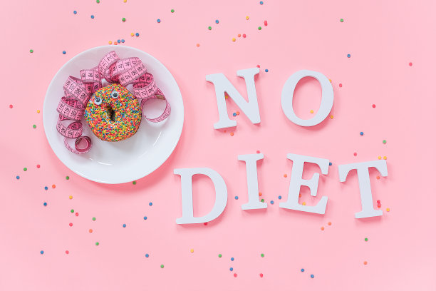 抽象有趣的脸的女人从甜甜圈与眼睛和头发从厘米胶带在盘子和文字没有饮食在粉红色的背景。概念国际无饮食日，6日可俯视图平躺图片下载