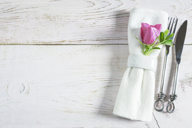 餐桌设置手工锻造的刀叉，白色亚麻餐巾与戒指和紫色的花图片下载
