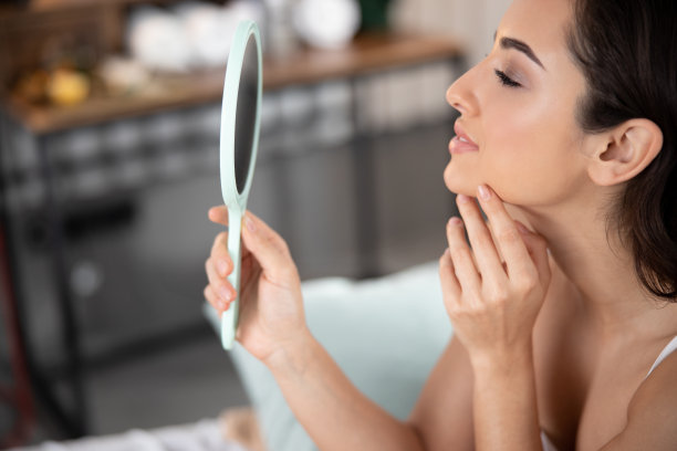 照镜子，触摸脸部的漂亮女人图片下载