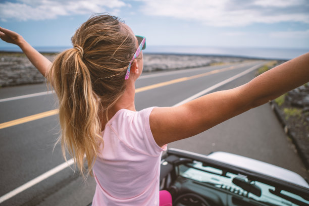 年轻女子坐在4x4汽车上，双臂伸开享受公路旅行图片下载