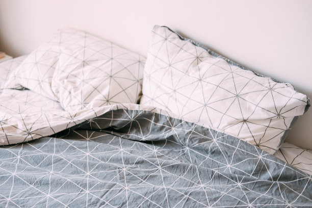 灰色和白色的凌乱的床。几何床单模式。图片下载