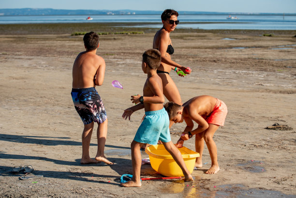 欢乐的家庭在泳衣与水炸弹在沙滩上在意大利-库存照片图片下载