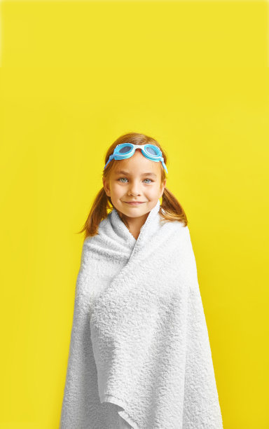 彩色背景上裹着毛巾、戴着泳镜的快乐儿童竖版照片图片下载