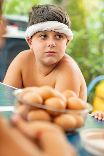 坚定的小男孩等待鸡蛋轮盘赌挑战戴着保护头带-股票照片图片下载