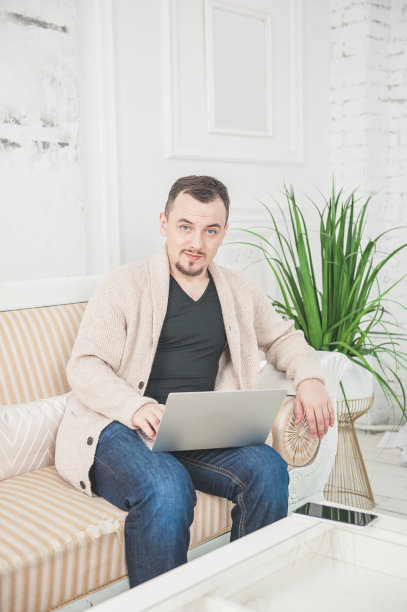 在家用笔记本电脑工作的快乐英俊男人图片下载