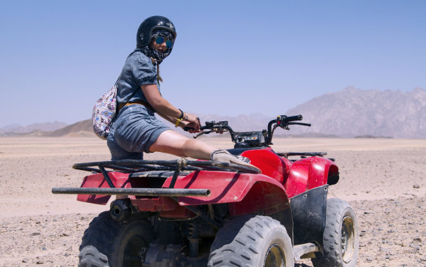 迷人女人在沙漠中驾驶四轮摩托车图片下载