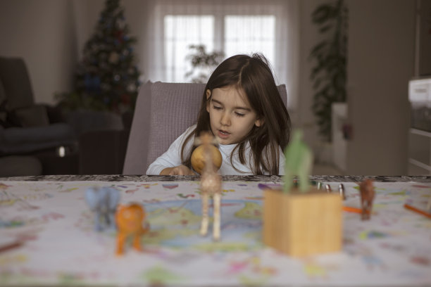 一个小女孩被塑料玩具动物和用铅笔画的木制几何图形包围着图片下载