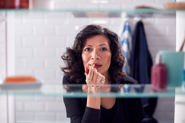 从浴室柜子里看成熟的女商人正在准备上班涂口红图片下载