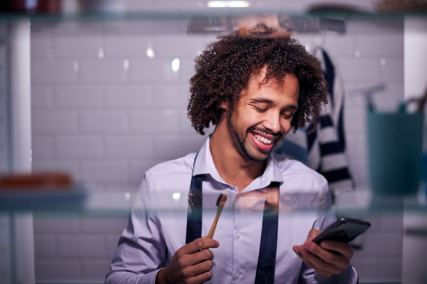 透过浴室柜看商人上班前刷牙和检查手机图片下载