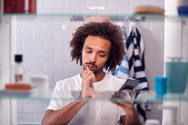 透过浴室柜，可以看到男士上班前刷牙和检查手机图片下载