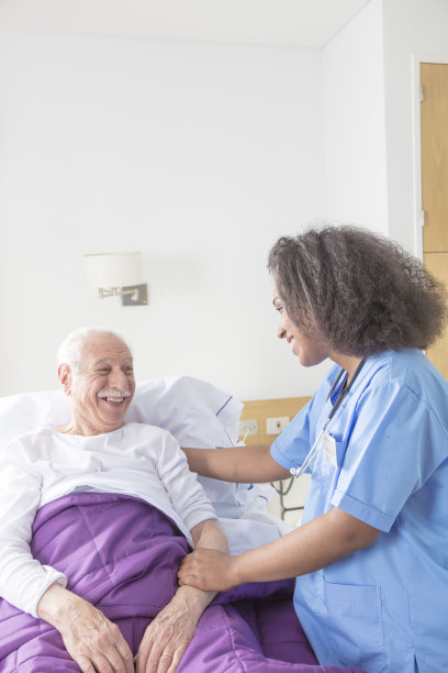 放心自信的非洲女医生访问老年高加索病人在医院的床上图片下载