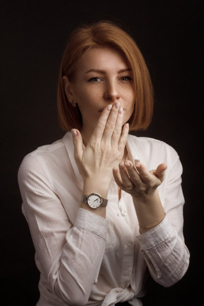 工作室的肖像，一个姜黄色的女孩与雀斑在白色的衬衫在一个黑色的背景。图片下载